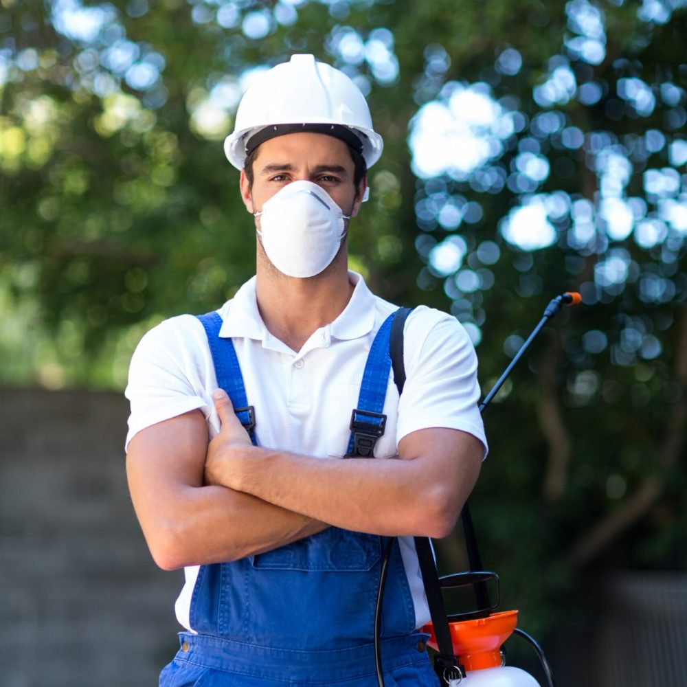 Portrait of confident pesticide worker with crossed arms standing in back yard